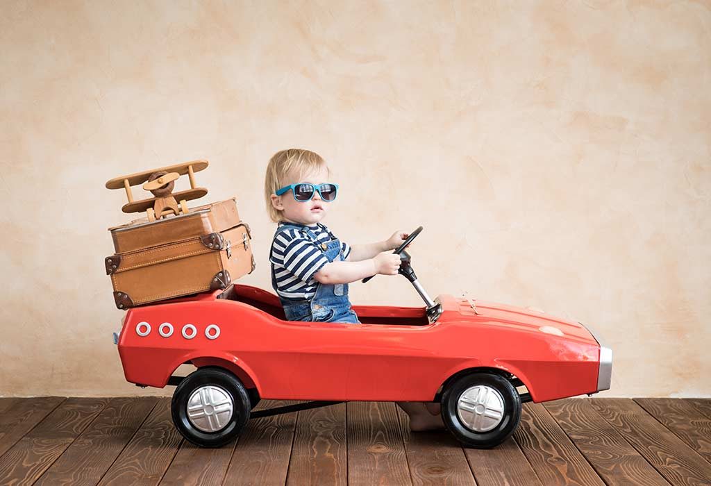ребенок за рулем игрушечной машины с багажом 