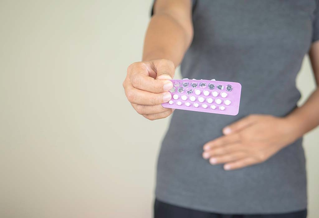 Женщина с противозачаточными таблетками в руке 