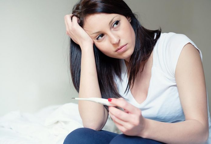 Приведенная в уныние женщина с палкой теста на беременность